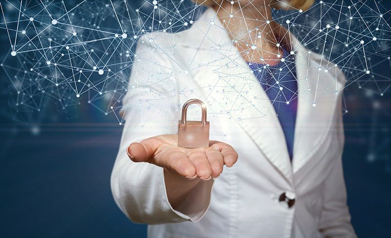 A person in a white coat holds a padlock in their hand representing the high level of security in IHSE's cyber security solutions. IHSE KVM systems are designed to mitigate cyber threats of most types, providing confidence in applications for all users.